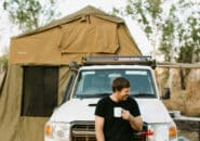 Man enjoying morning coffee in front of 4WD with rooftop tent on a Kimberley camping tour.