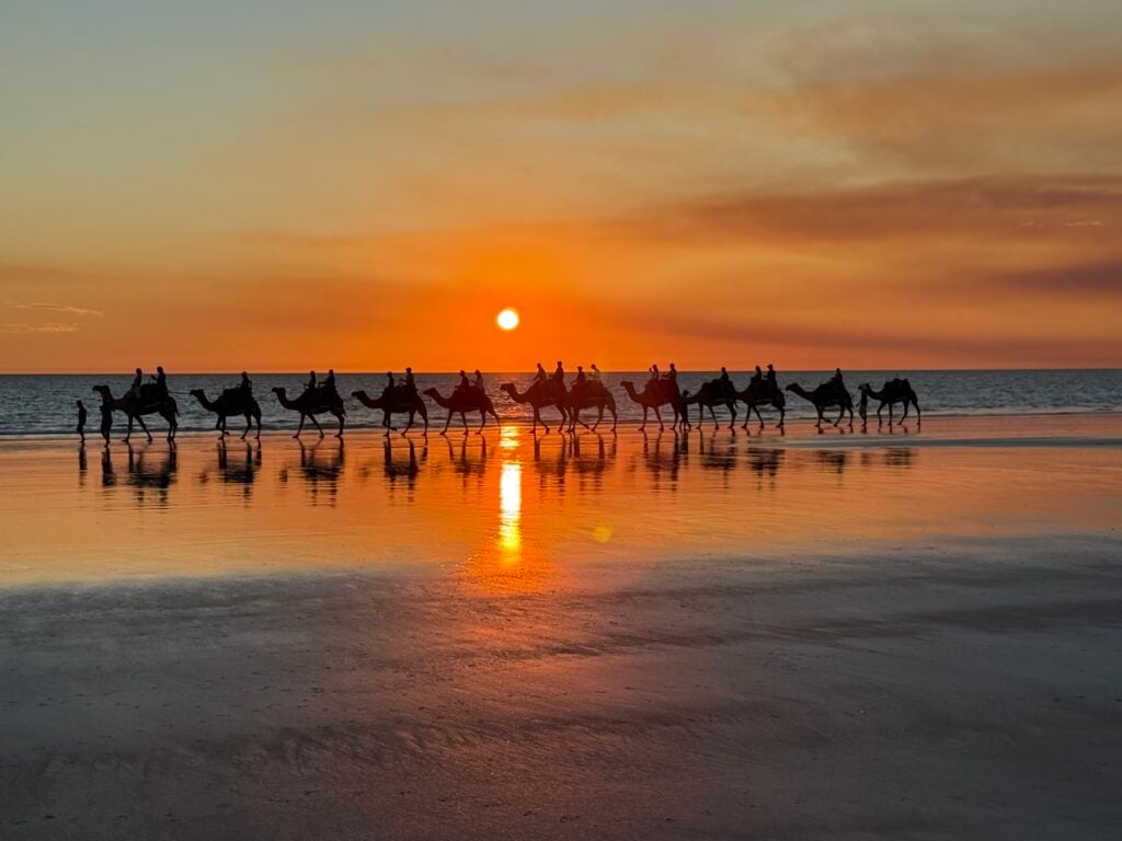 Sunset on Cable Beach in Broome with people a camel ride